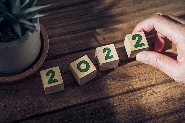 2022 happy new year with hand pick up wood block on wood table with sunlight from window.hope for new year concept