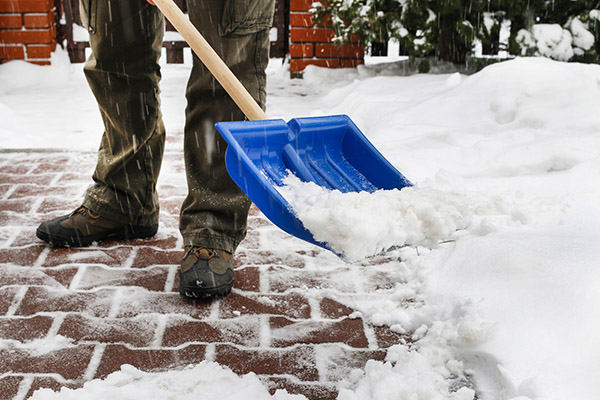 Man removing snow from the sidewalk after snowstorm. Winter work