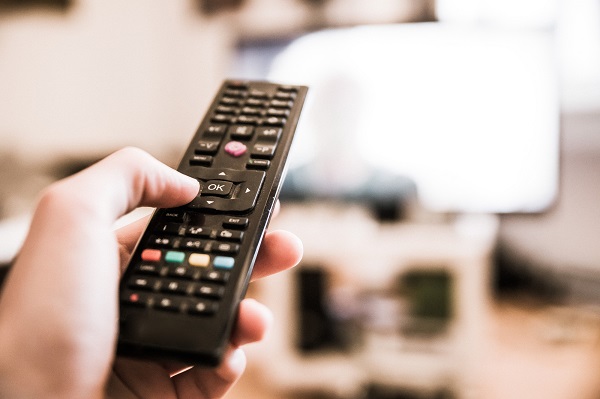 Male hand is holding TV remote control, smart TV.